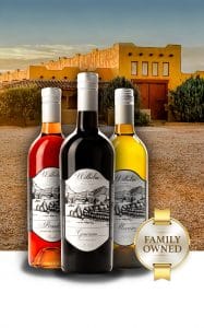 Three bottles of wine in front of our winery with a "family owned" logo