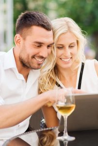 A couple purchases wines online while sitting outside